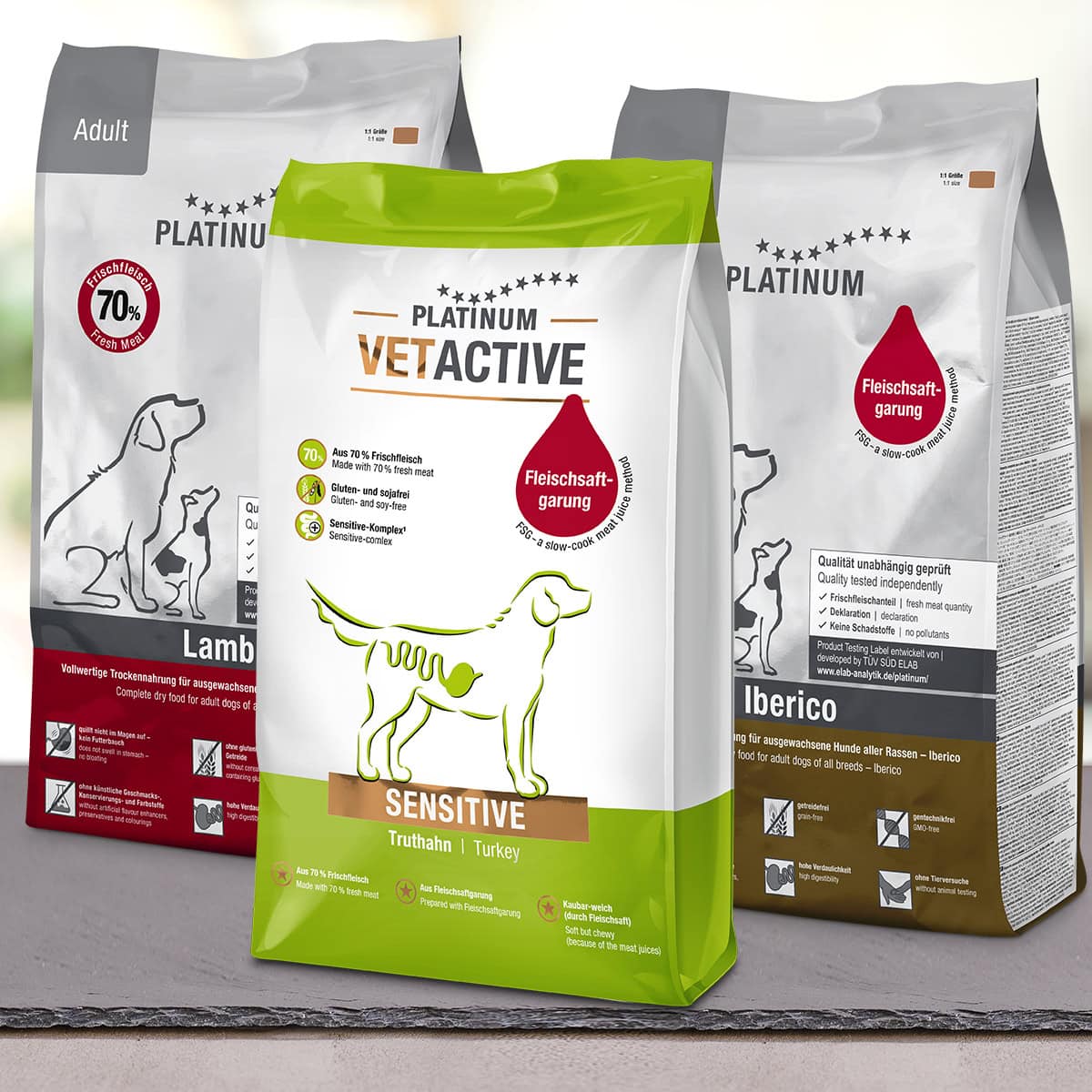 Tri vrečke PLATINUM Paket različnih okusov Suhe Hrane za Pse stojijo skupaj, vsaka prikazuje ilustriranega psa in poudarja naravne sestavine v okusih Sensitive Turkey, Lamb in Iberico.