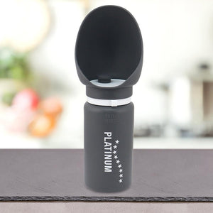 Siv Prenosni bidon z lijakom za pse blagovne znamke PLATINUM z vgrajeno posodo za vodo je postavljen na pult v zamegljenem notranjem okolju.