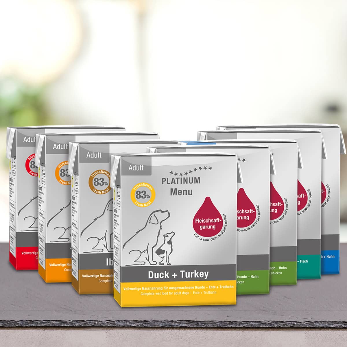Več paketov PLATINUM Paket različnih okusov Mokre Hrane za Pse je postavljenih v vrsto, z etiketo okusov kot Duck + Turkey ter embalažo, ki poudarja visoko prebavljivost in slike psov z opisi okusov v nemščini.